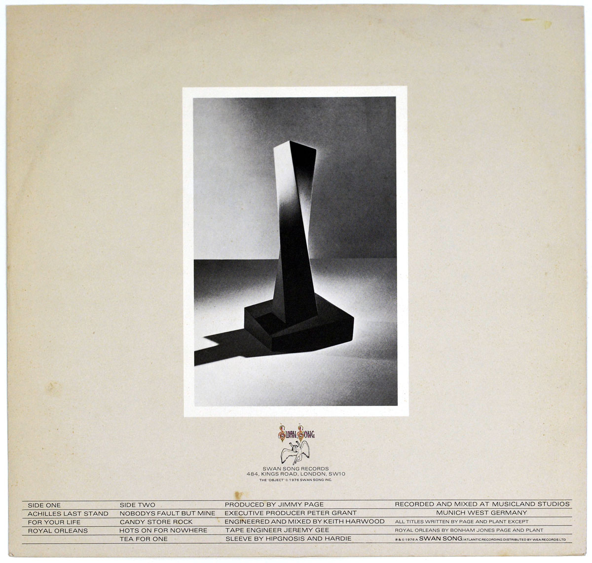 Back cover of Led Zeppelin's 'Presence' album, featuring a black-and-white photograph of a mysterious black obelisk-like object casting a sharp shadow. Below, track listings, production credits, and the Swan Song Records logo are displayed.